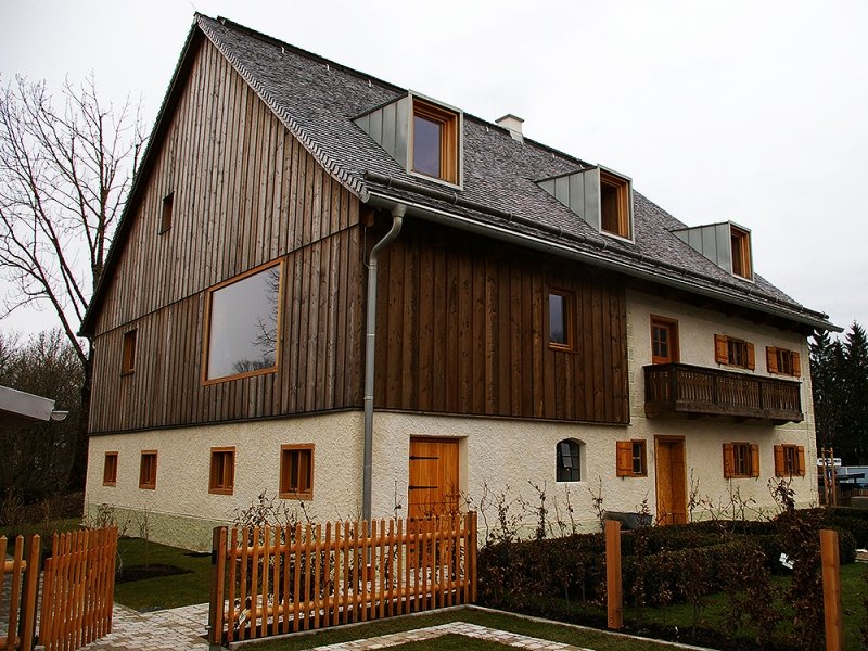 Ehemaliges Bauernhaus mit Holzverschalung im Obergeschoss und Fensterläden