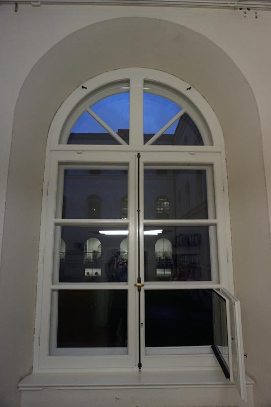 Rundbogenfenster mit Sprossen in einer hellen Laibung