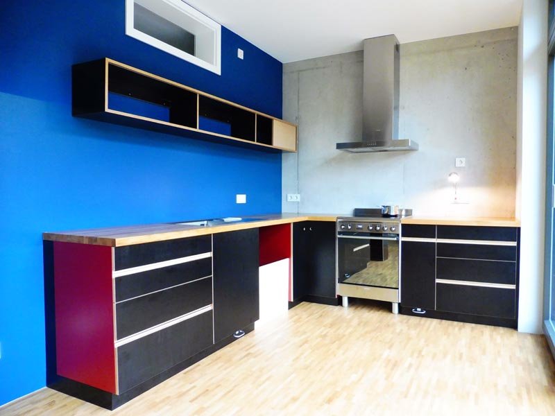 Küchenzeile mit schwarzen und roten Fronten vor einer blauen Wand