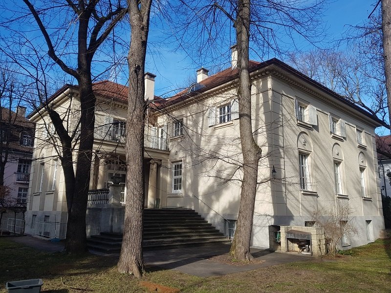 Stadthaus mit Holzfenstern hinter Bäumen